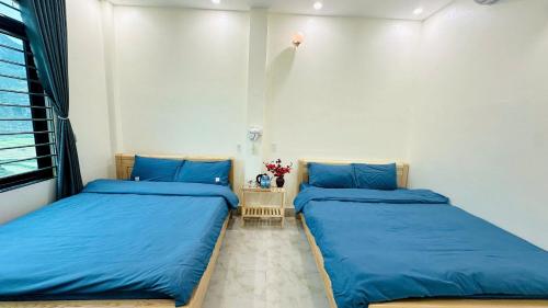 two beds in a room with blue sheets at ToTo-Chan Hotel in Dồng Văn
