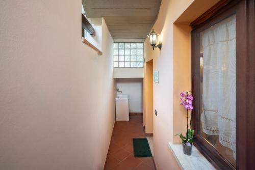 a hallway with a window and purple flowers in a vase at Follonica Apartments - Pool & Relax in Follonica