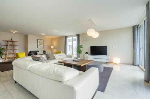 a living room with a white couch and a tv at Montreux Lake View Apartments and Spa - Swiss Hotel Apartments in Montreux