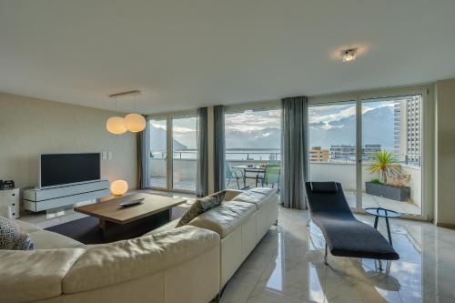 a living room with a large couch and a television at Montreux Lake View Apartments and Spa - Swiss Hotel Apartments in Montreux