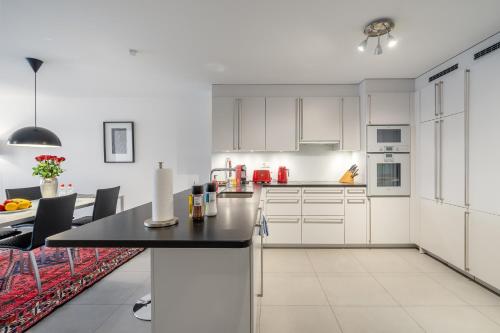a kitchen with white cabinets and a black counter top at Montreux Lake View Apartments and Spa - Swiss Hotel Apartments in Montreux