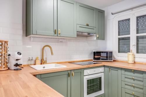 a kitchen with green cabinets and a sink at Ultimate Rentals - Gezellig Stijlvol Appartement Dichtbij Het Strand - Communal Pool in Estepona