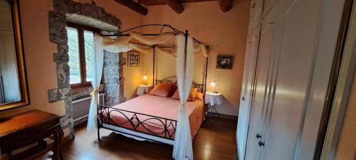 une chambre avec un lit à baldaquin dans une pièce dans l'établissement Le Mas de Largellas, à Balazuc