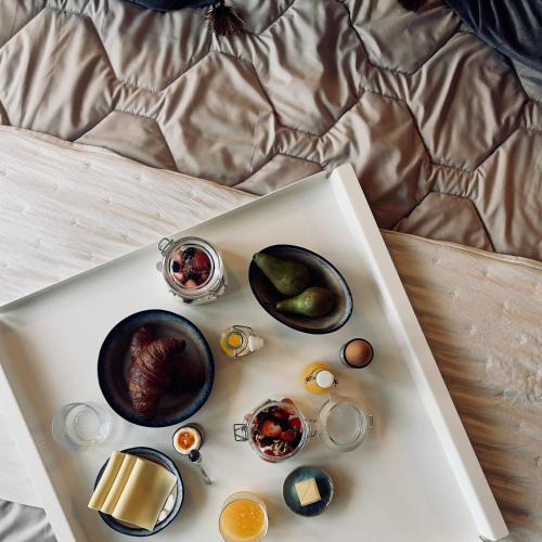 a tray with eggs and other food on a bed at Wiltsangh Texel Tuinsuite Black in De Waal