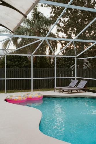 a swimming pool with two chairs and a bench at Luxury Private Pool Villa near Disney with Fire Pit, Game Room & More in Kissimmee