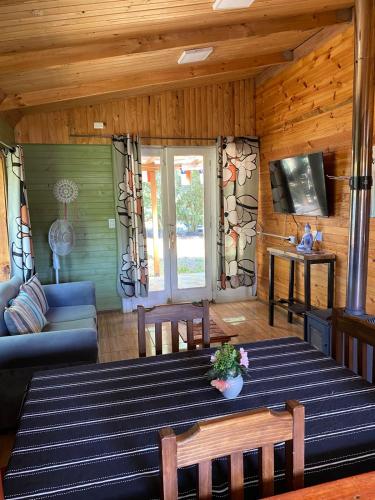 a living room with a table and a couch at Las palmeras de Colbún in Colbún