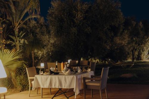 a dining table with a white table cloth and chairs at Les Roses By La Siredrah in Marrakech