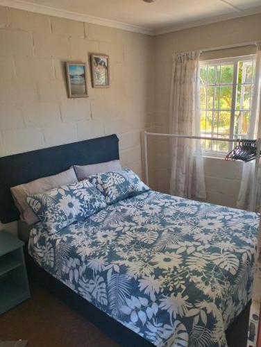 a bedroom with a bed with a blue and white blanket at Its Practical Holidays in Hermanus