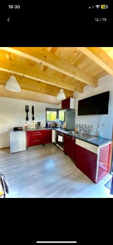 Il comprend une grande cuisine dotée de plafonds en bois et de placards rouges. dans l'établissement Cottage balnéo vue mer, à Bazenville