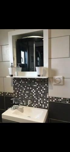 une salle de bain avec un lavabo et un miroir dans l'établissement Cottage balnéo vue mer, à Bazenville