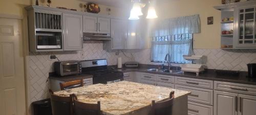 a kitchen with white cabinets and a table with a microwave at Luxury Vacation Villa St Catherine in Spanish Town