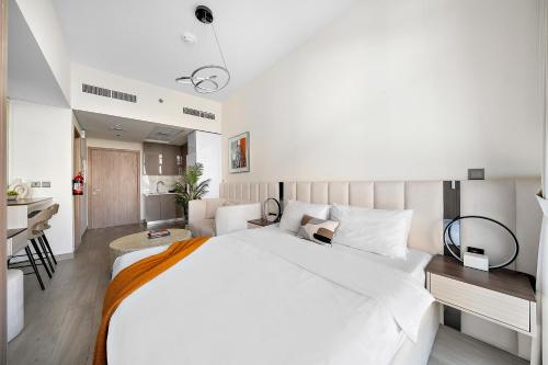 a bedroom with a large white bed and a kitchen at Studio Azizi Riviera 35, Community View in Dubai