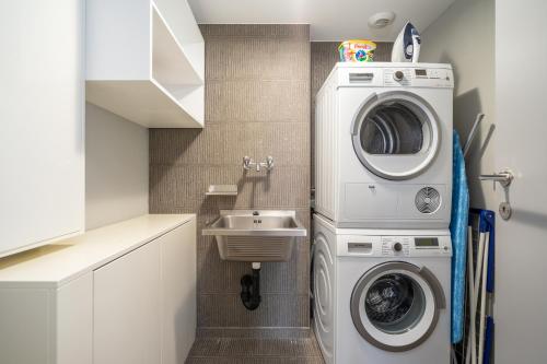 a small bathroom with a washing machine and a sink at Montreux Lake View Apartments and Spa - Swiss Hotel Apartments in Montreux