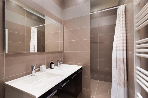 une salle de bain avec un lavabo et un miroir dans l'établissement charmant et chaleureux paris 17ème, à Paris