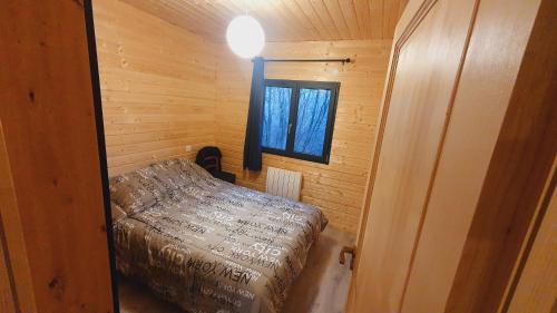 Cette petite chambre comprend un lit dans une cabane en bois. dans l'établissement Le Chalet du Grand Megnaud, à La Tour-dʼAuvergne