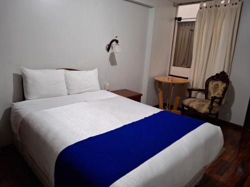 a bedroom with a blue and white bed and a chair at Hotel Sideral AQP in Arequipa