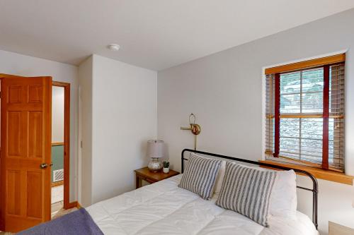 a white bedroom with a bed and a window at Riverfront Retreat in Sagle