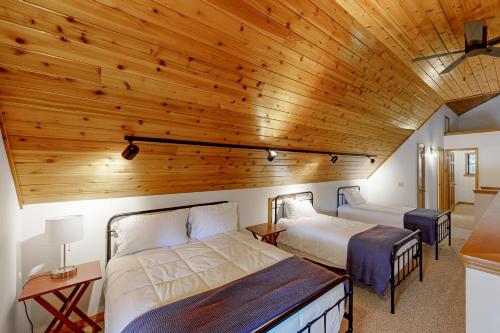 a bedroom with two beds and a wooden ceiling at Riverfront Retreat in Sagle