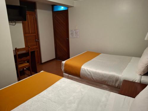 a hotel room with two beds and a television at Hotel Sideral AQP in Arequipa