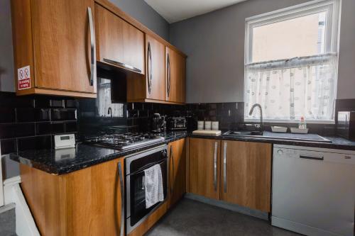 a kitchen with wooden cabinets and a stove top oven at Hullidays City Centre Urban Apartment 2 in Hull