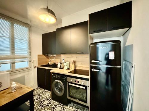 La cuisine est équipée d'un réfrigérateur noir et d'un lave-vaisselle. dans l'établissement CAPITOLE - Appartement T2 au cœur de la ville rose, à Toulouse