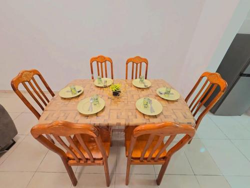 a wooden table with four chairs and plates on it at SD Home in Rawang in Batu Arang