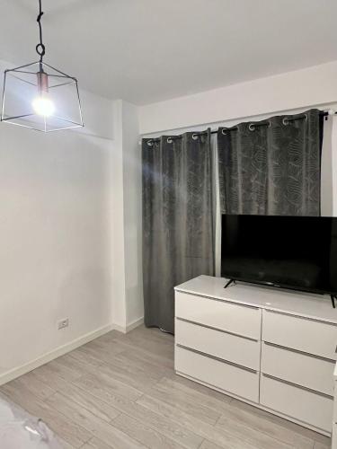un salon avec une télévision et une commode blanche dans l'établissement One, à Craiova