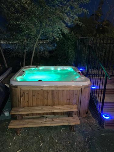 a hot tub with a bench in a yard at night at צימר מול השקיעה in Retamim