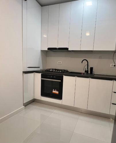 une cuisine avec des armoires blanches et un four noir dans l'établissement One, à Craiova