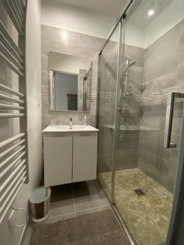 La salle de bains est pourvue d'un lavabo et d'une douche avec une porte en verre. dans l'établissement La grange des plagnettes, à Montpezat-de-Quercy