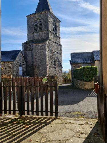 an old church with a clock tower behind a fence at Maison de village Estalane in Castelnau-Pégayrols