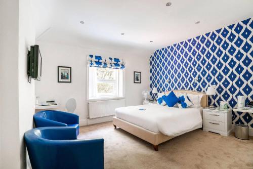 a blue and white bedroom with a bed and two blue chairs at Balincourt in Bournemouth
