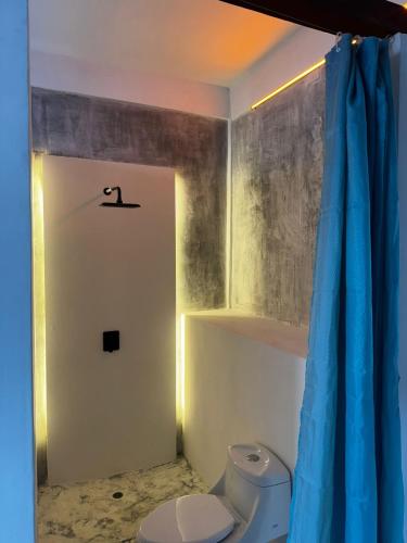 a bathroom with a toilet and a blue curtain at Miterio Mundo Nuevo in Minca