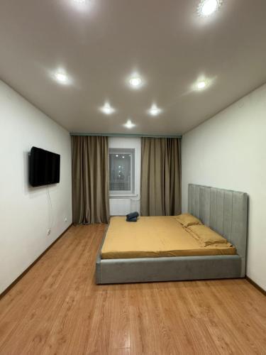 a bedroom with a bed and a flat screen tv at Apartments Zhayau Musa 7b in Pavlodar