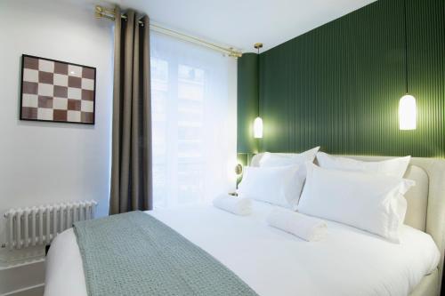 a bedroom with a white bed with a green wall at Appartement élégant près de Bastille-Gare de Lyon in Paris