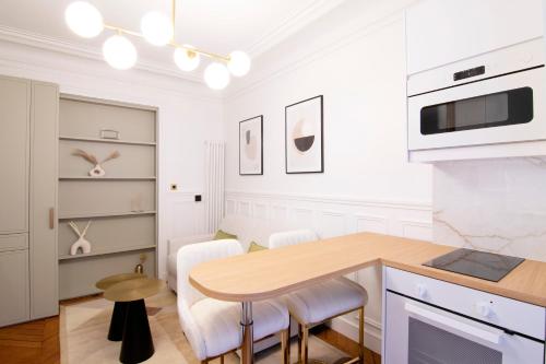 - une cuisine blanche avec une table et des chaises en bois dans l'établissement Appartement élégant près de Bastille-Gare de Lyon, à Paris