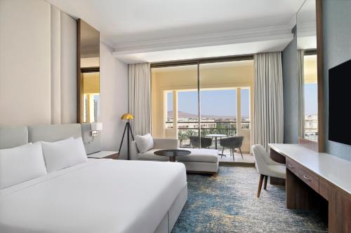 a hotel room with a bed and a living room at Mövenpick Hotel Waad Al Shamal in Ţurayf