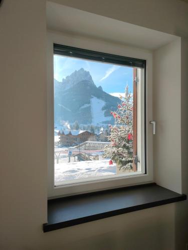 a window with a christmas tree and a mountain at appartamento PANORAMA in Pozza di Fassa
