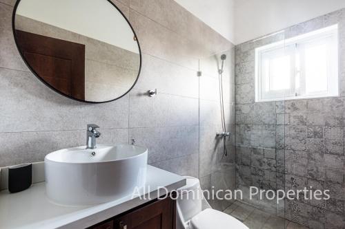 een badkamer met een witte wastafel en een spiegel bij Villas Santa Fe in Sosúa