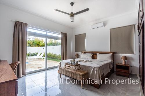 een slaapkamer met een bed, een tafel en een raam bij Villas Santa Fe in Sosúa