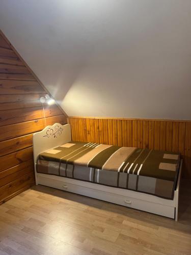 a bed in a room with a wooden wall at Rojaus Slenis in Druskininkai