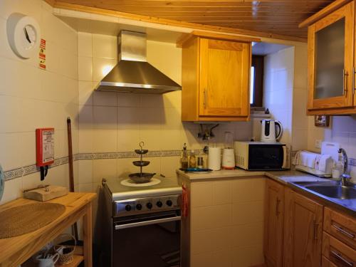 a small kitchen with a stove and a microwave at O Cantinho de Góis in Góis