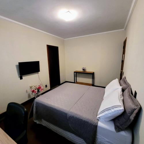 a small bedroom with a bed and a television at Blu Hostel in Blumenau