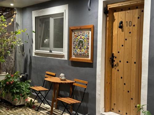 a table and chairs next to a wall with a door at Ziv Boutique Apartments Town Square II in Lefkada Town