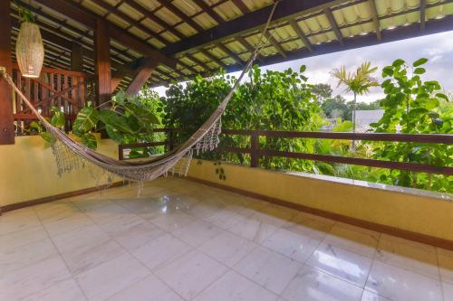 a hammock on the balcony of a house with trees at Apartamentos Breezes com verde, sossego e preço justo - ideal para famílias e amigos em Imbassaí in Imbassai