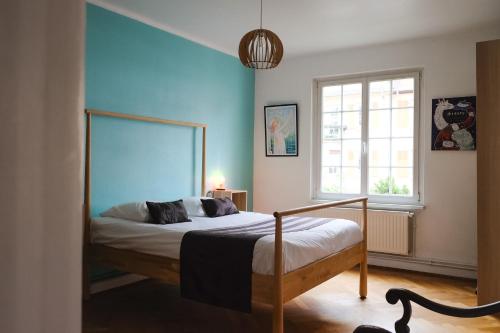 une chambre avec un lit avec un mur bleu dans l'établissement Chez Schätzele - Joli appartement Strasbourgeois, à Strasbourg