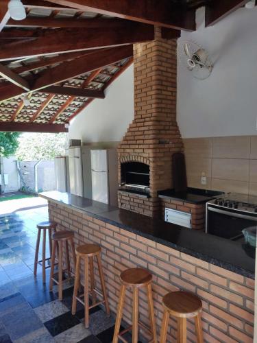 a kitchen with four stools and a brick oven at Rancho Costa in Pereira Barreto