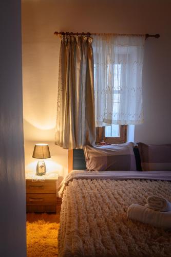 a bedroom with a bed with a window and a lamp at Konaki inn in Palaios Agios Athanasios