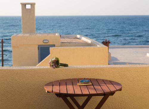 a small wooden table on the side of a wall with the ocean at Porto Sisi Hotel Apartments in Sissi