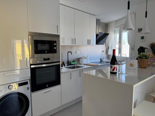 a kitchen with white cabinets and a stove top oven at Cabosun in El Cabo de Gata